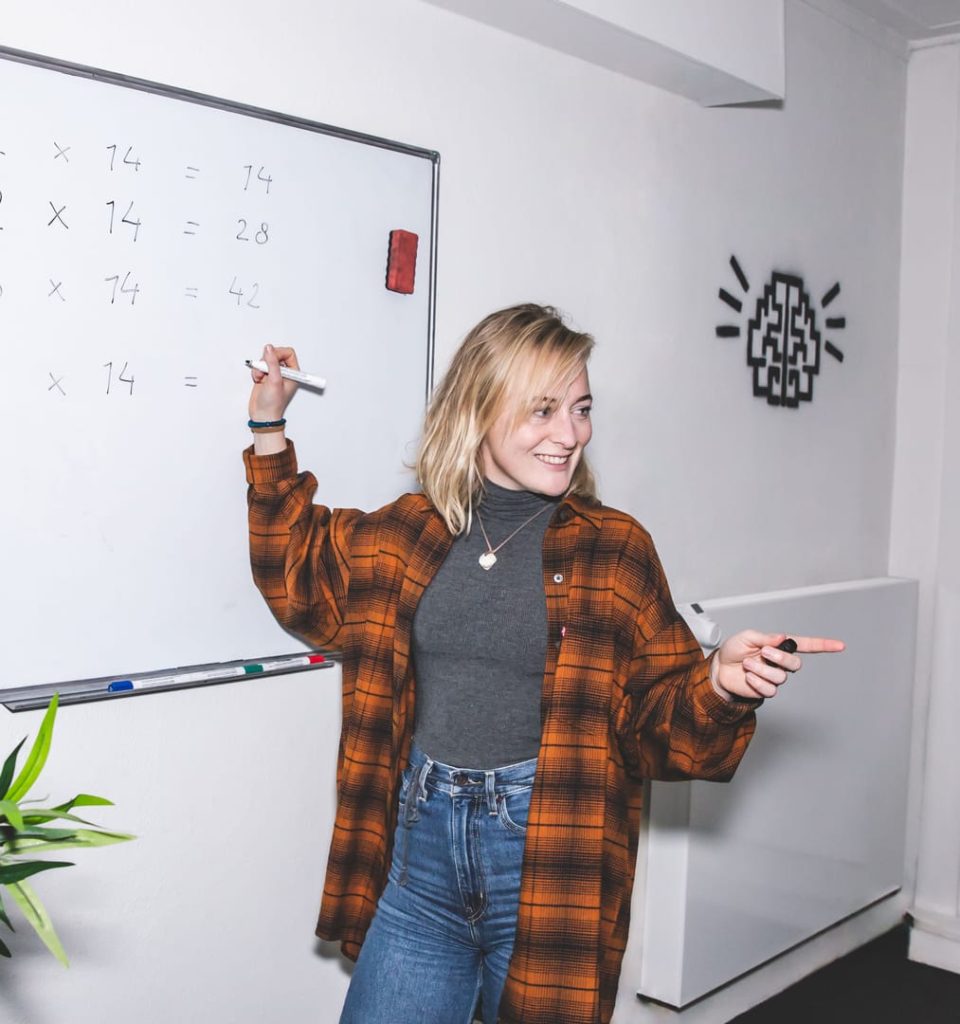 Brainboost docent schrijft vermenigvuldigingstafels op whiteboard tijdens wiskunde bijles